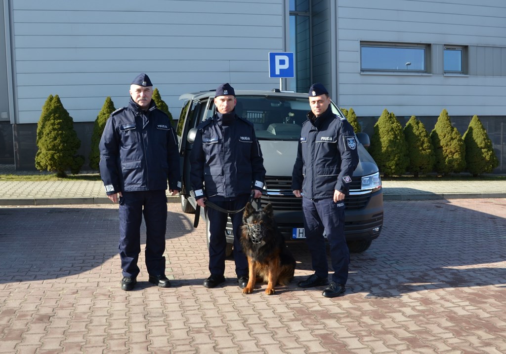 wspólne zdjęcie przed nowym radiowozem - komendant, naczelnik oraz przewodnik z psem służbowym