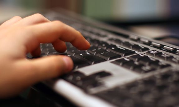 dziecięca dłoń pisząca na klawiaturze komputera