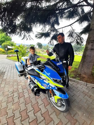 chłopiec na policyjnym motocyklu, obok funkcjonariusz ruchu drogowego