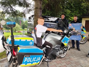 chłopiec na służbowym motocyklu, obok dwóch policjantów