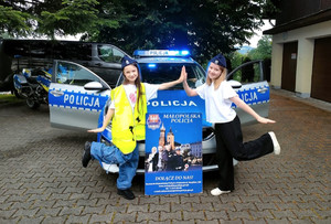 dwie dziewczynki przy radiowozie i plakacie zachęcającym do wstąpienia w szeregi Policji — kopia