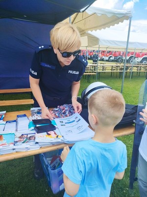 chłopiec odbiera od policjantki pamiątkowy dyplom ze swoimi liniami papilarnymi