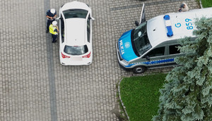 policjanci prowadzą kontrolę drogową, obok oznakowany radiowóz