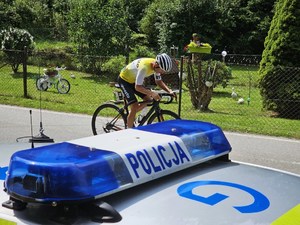 lampa błyskowa na dachu radiowozu, w tle jadący kolarz