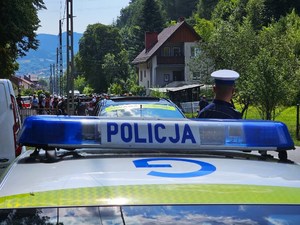 policjant ruchu drogowego przy radiowozie, w tle zawodnicy