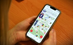 kobieta trzyma w dłoniach telefon komórkowy, na ekranie KMZB w rejonie Nowego Sącza