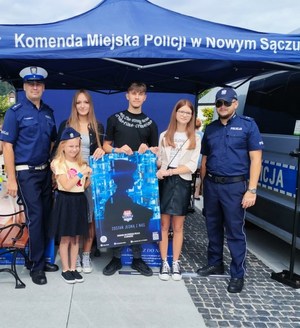 wspólne zdjęcie policjantów i nastolatków z plakatem zachęcającym do wstąpienia do Policji-