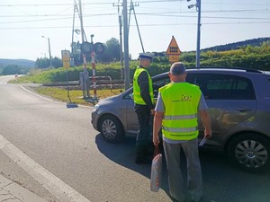 policjant i przedstawiciel PKP podchodzą do samochodu osobowego, okolice przejazdu kolejowo-drogowego