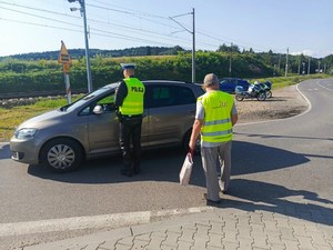 policjant rozmawia z kierującym, obok pracownik PKP