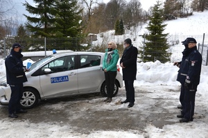 Komendant trzymając w ręku pamiątkową statuetkę dziękuje za okazane wsparcie, w tle nowy radiowóz, obok uczestnicy spotkania