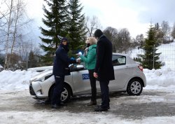 Przewodnicząca Rady Miejskiej przekazuje Komendantowi kluczyki do radiowozu, w tle nowy pojazd służbowy
