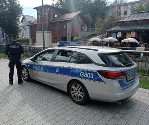 7. Radiowóz oznakowany  obok  umundurowany policjant - zabezpieczenie prewencyjne forum Krynica