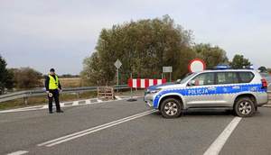 Policjant z KMP w Nowym Saczu  kieruje ruchem obok radiowóz oznakowany