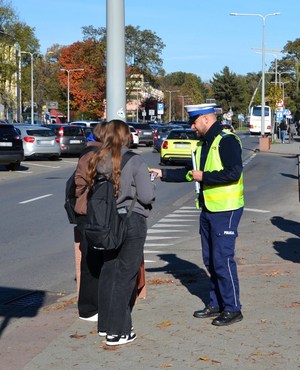 6. policjant przekazuje nastolatkom elementy odblaskowe