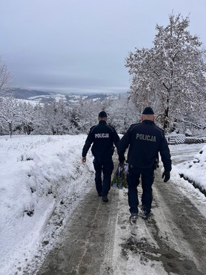 dzielnicowi idą z prezentami zaśnieżoną drogą