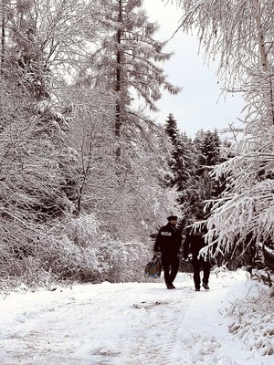 policjanci niosą prezenty idąc zaśnieżoną drogą