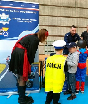 Chłopiec w kamizelce odblaskowej z napisem Policja przy stoisku edukacyjnym Policji