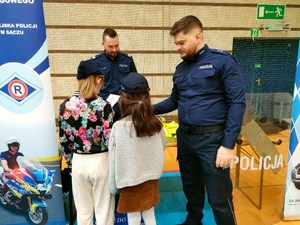 Policjant wręczający dzieciom ulotki profilaktyczne