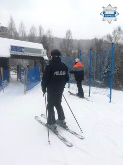 policjant na stoku, obok narciarz