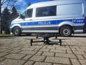 Policyjny dron, obok oznakowany radiowóz