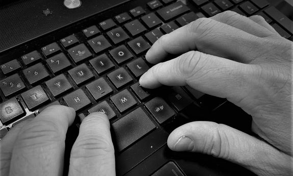 męska dłoń pisząca na klawiaturze komputera