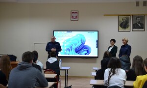 Komendant rozmawia z uczniami, obok dyrektor szkoły i policjantka