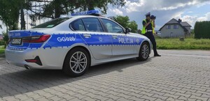 policjantka ruchu drogowego przy oznakowanym radiowozie, w dłoniach trzyma laserowy miernik prędkości