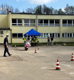 uczestnik na motorowerze, obok policjant