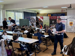 policjanci rozdają uczestnikom testy wiedzy