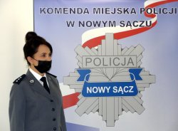 emerytowana policjantka na tle baneru sądeckiej Policji