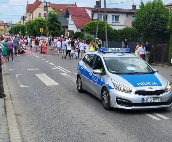 policyjny radiowóz i uczestnicy procesji
