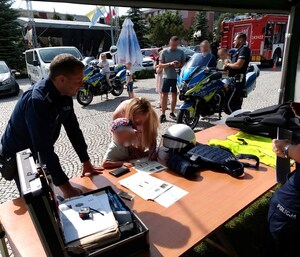 dziecko odbija linie papilarne, w tle pojazdy Policji