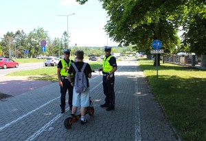 policjanci rozmawiają z użytkownikiem hulajnogi elektrycznej