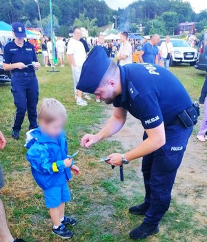 policjant przekazuje chłopcu odblask i ulotkę