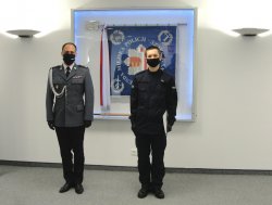 wspólne zdjęcie Komendanta i nowego policjanta na tle sztandaru