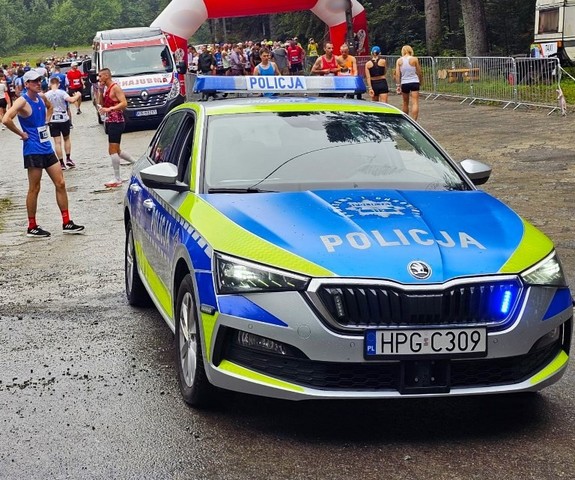 oznakowany radiowóz w pobliżu startu jednego z biegów, w tle zawodnicy — kopia