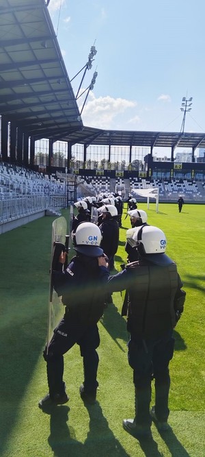 funkcjonariusze prewencji w kaskach i z tarczami ochronnymi na murawie stadionu