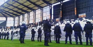 policjanci stoją przed sektorami, inni wchodzą na murawę