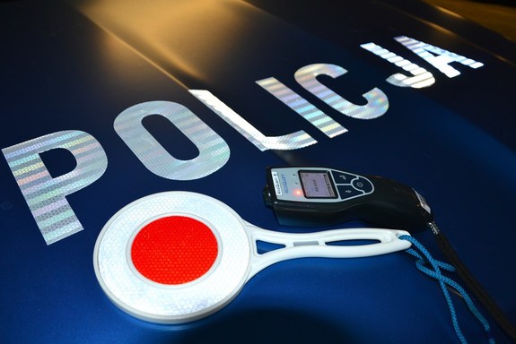 alkomat i tarcza do zatrzymywania pojazdów położone na masce radiowozu, obok widoczny napis Policja