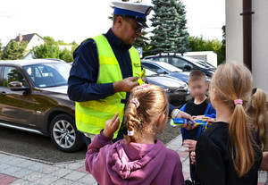 policjant wręcza dzieciom odblaski