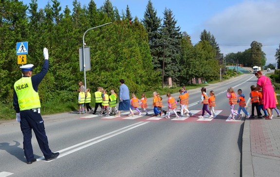funkcjonariusz drogówki wstrzymuje ruch, uczniowie przechodzą przez przejście dla pieszych — kopia