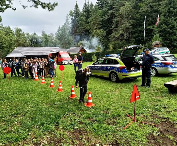 chłopiec w goglach pokonuje tor przeszkód obok policjanci, radiowozy i inni uczestnicy