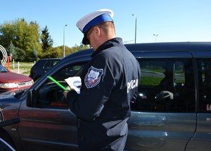policjant wręcza kierowcy element odblaskowy i naklejkę akcji Mistrzu zwolnij