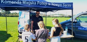 stoisko profilaktyczno-edukacyjne sądeckiej komendy, troje dzieci ogląda sprzęt służbowy