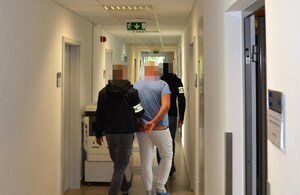 nieumundurowani policjanci prowadzą zatrzymanego korytarzem komendy