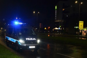 noc, oznakowany radiowóz z włączonymi sygnałami świetlnymi