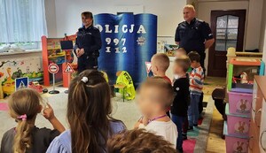 policjantka i policjant tłumaczą dzieciom jak bezpiecznie zachowywać się w ruchu drogowym