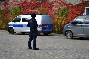 policjant zabezpiecza teren, w tle oznakowany i nieoznakowany radiowóz