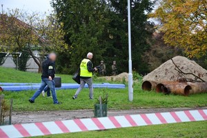 nieumundurowani policjanci, w tym technik kryminalistyki, w tle strażnicy graniczni