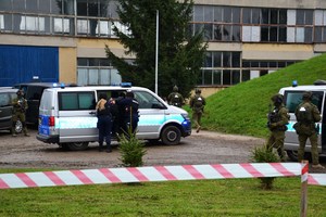 policjanci wprowadzają zatrzymanego do oznakowanego radiowozu